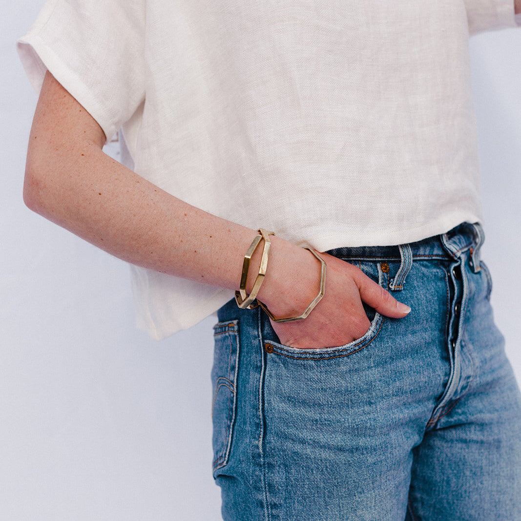 brass octagon bangle bracelets on model wearing jeans